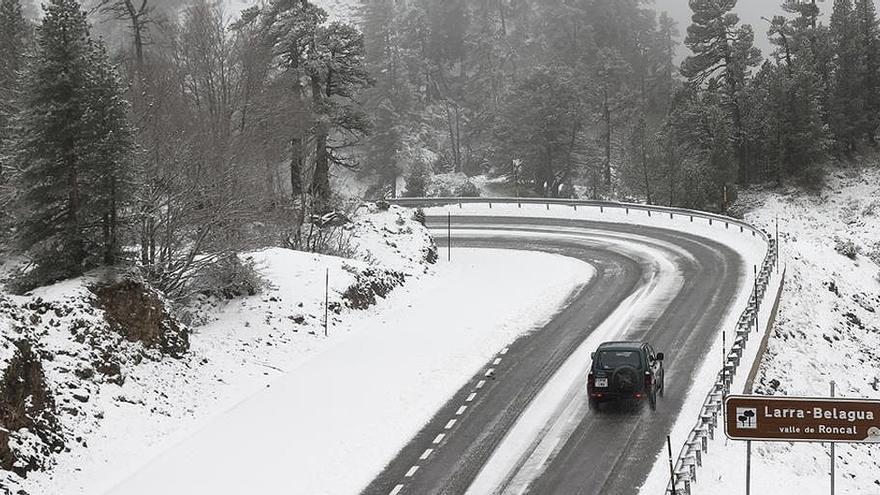 Un coche circula por un paisaje nevado.