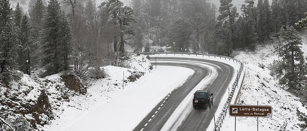 Un coche circula por un paisaje nevado.