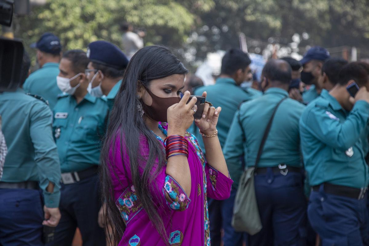 Una mujer toma fotos con su móvil mientras participa en una manifestación con motivo del Día Internacional de la Mujer en Daca (Bangladesh).