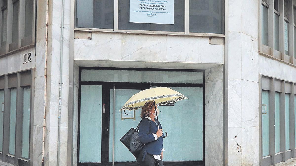 Una mujer pasa frente a una de las oficinas bancarias cerradas en el Grau de Castelló.