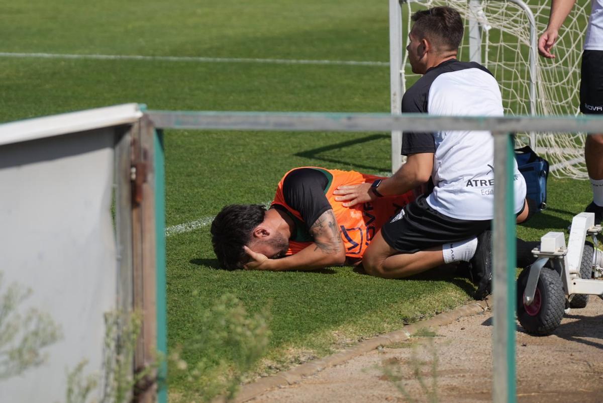 Adri Castellano se duele de su lesión y es atendido por un fisio del Córdoba CF, este miércoles, en la Ciudad Deportiva.