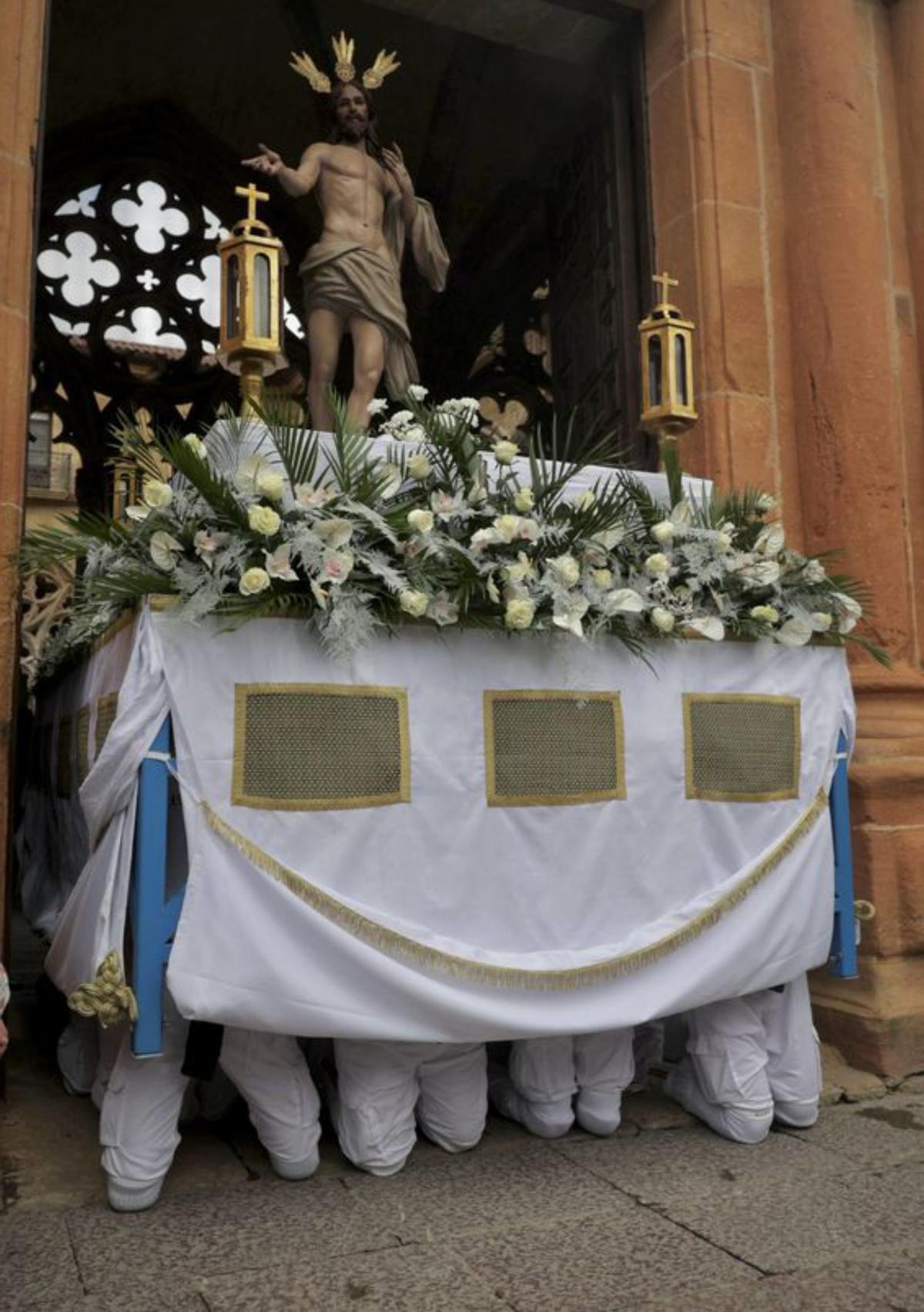 Los costaleros, de rodillas, al inicio de la procesión. | IRMA COLLÍN