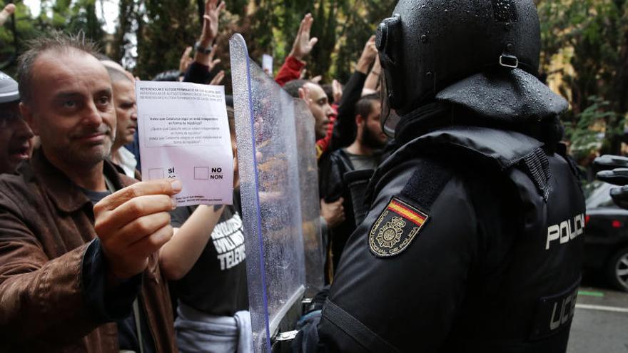 Un votant amb una papereta davant d&#039;un antidisturbis.