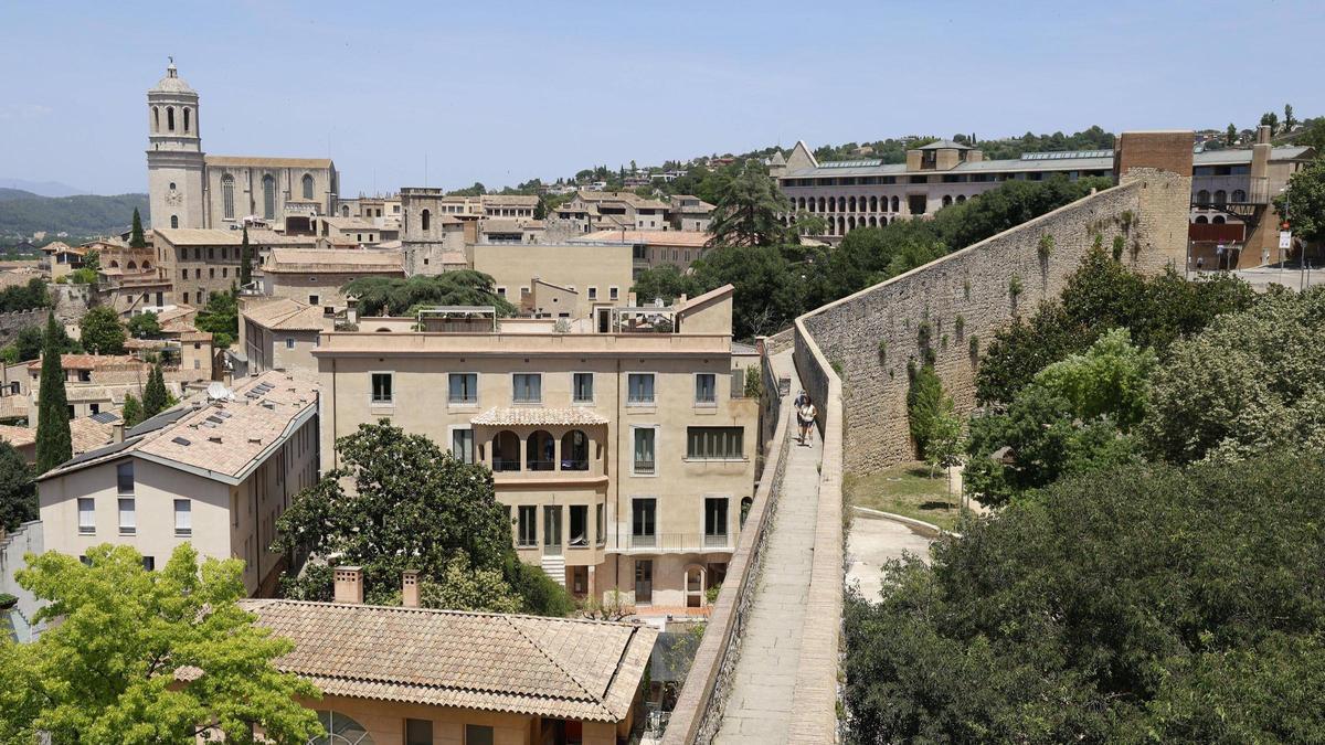 Un parell de turistes passegen per la muralla de Girona.