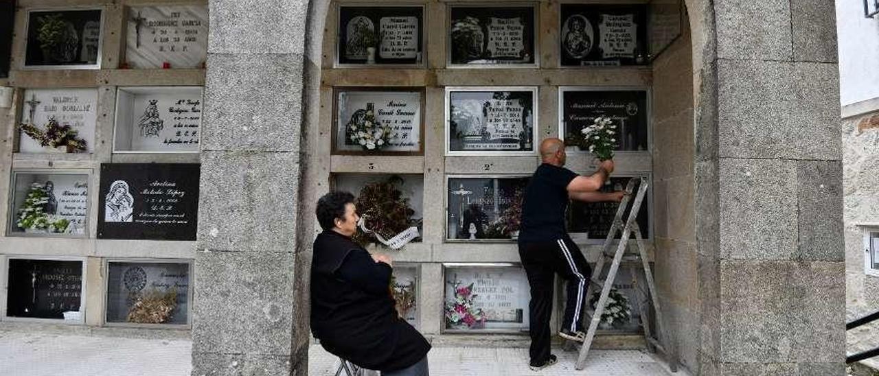 Un hombre sube a colocar flores en uno de los nichos del cementerio de Marín. // Gustavo Santos