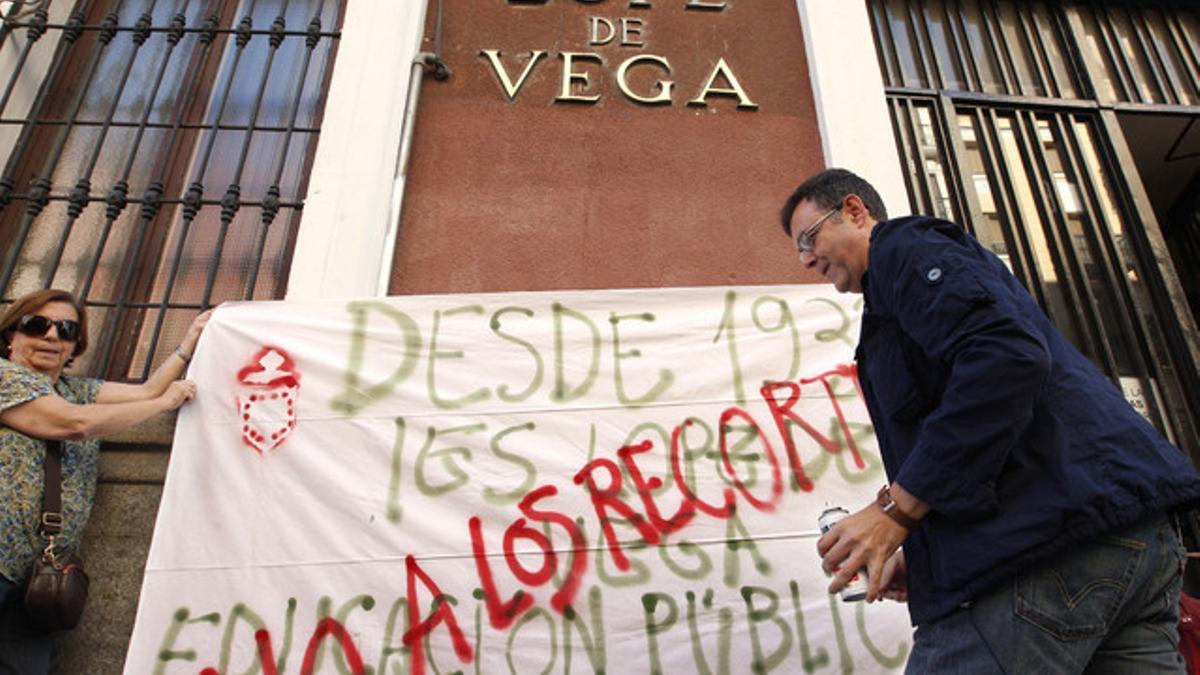 Dos profesores colocan una pancarta en la fachada del IES Lope de Vega de Madrid, hoy.