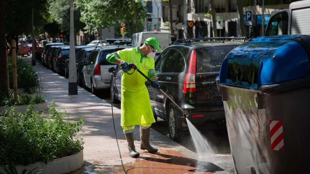 Un trabajador de los servicios de limpieza desinfecta un contenedor en Barcelona este lunes.