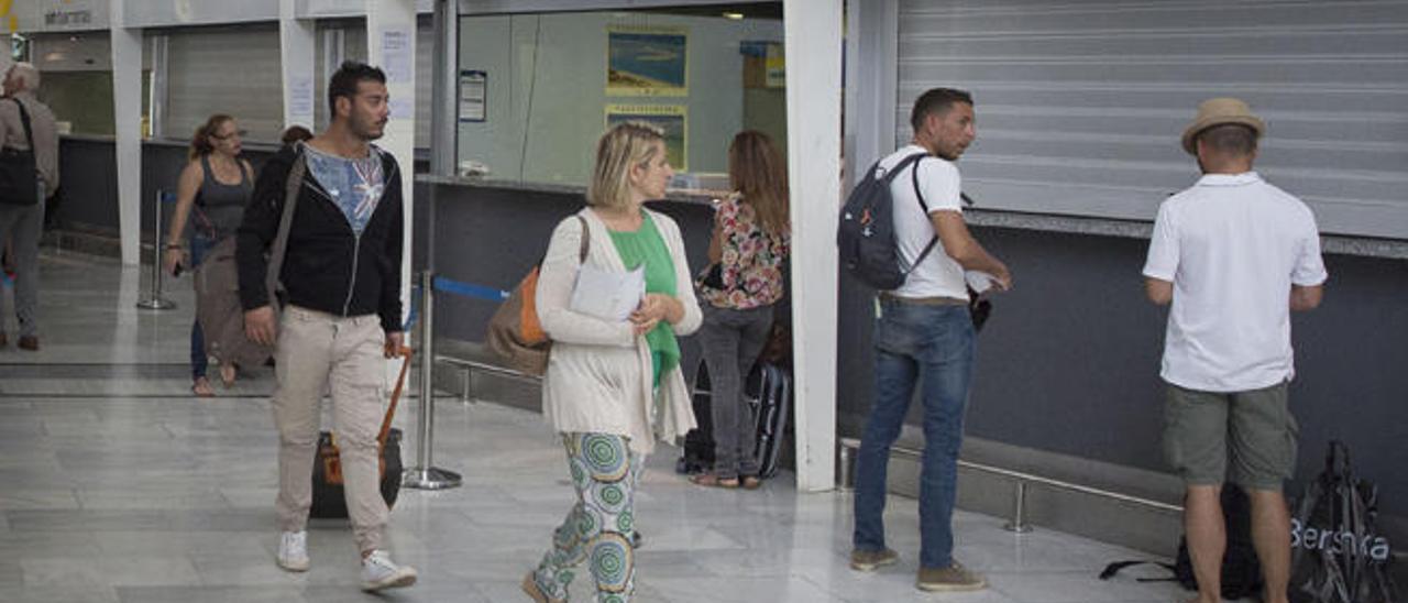 Varios pasajeros caminan delante de las oficinas de Ryanair en el aeropuerto de Fuerteventura, ayer.