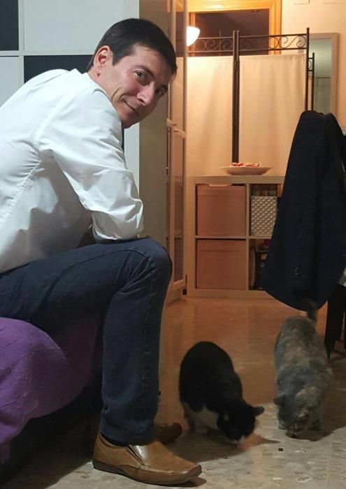 El alcalde de Burjassot, Rafa García, da de comer a sus dos gatas, Lluna y Fiona.