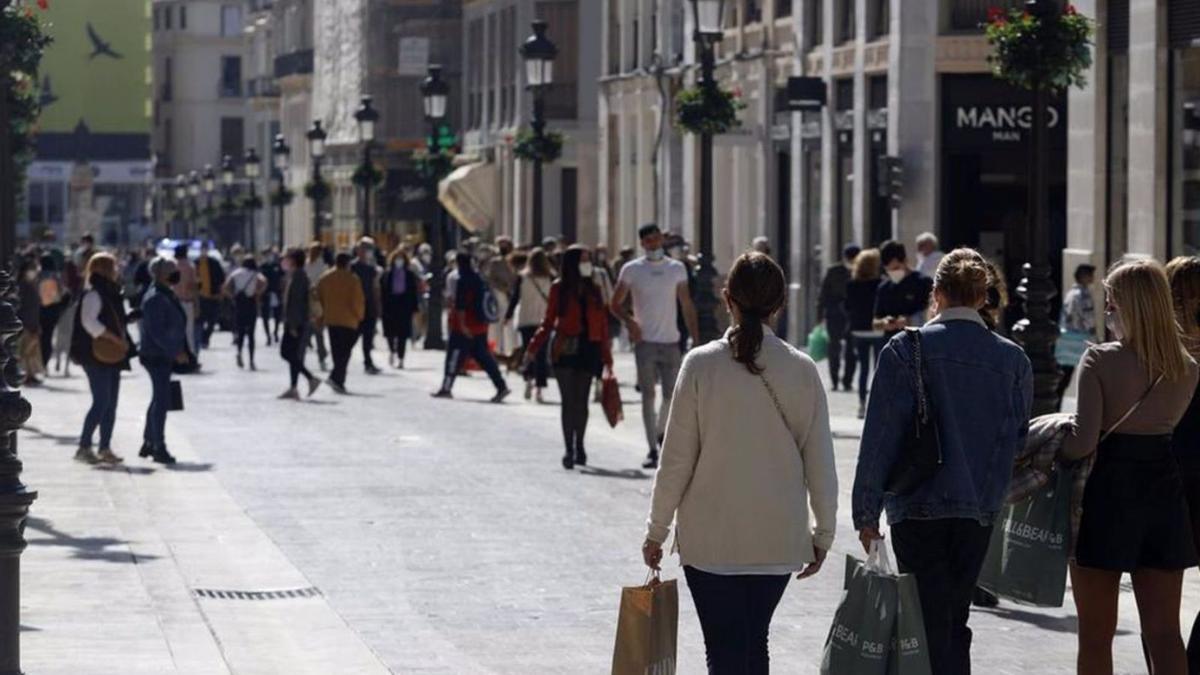 Peatones transitan por la calle Larios con bolsas de compras. | ÁLEX ZEA