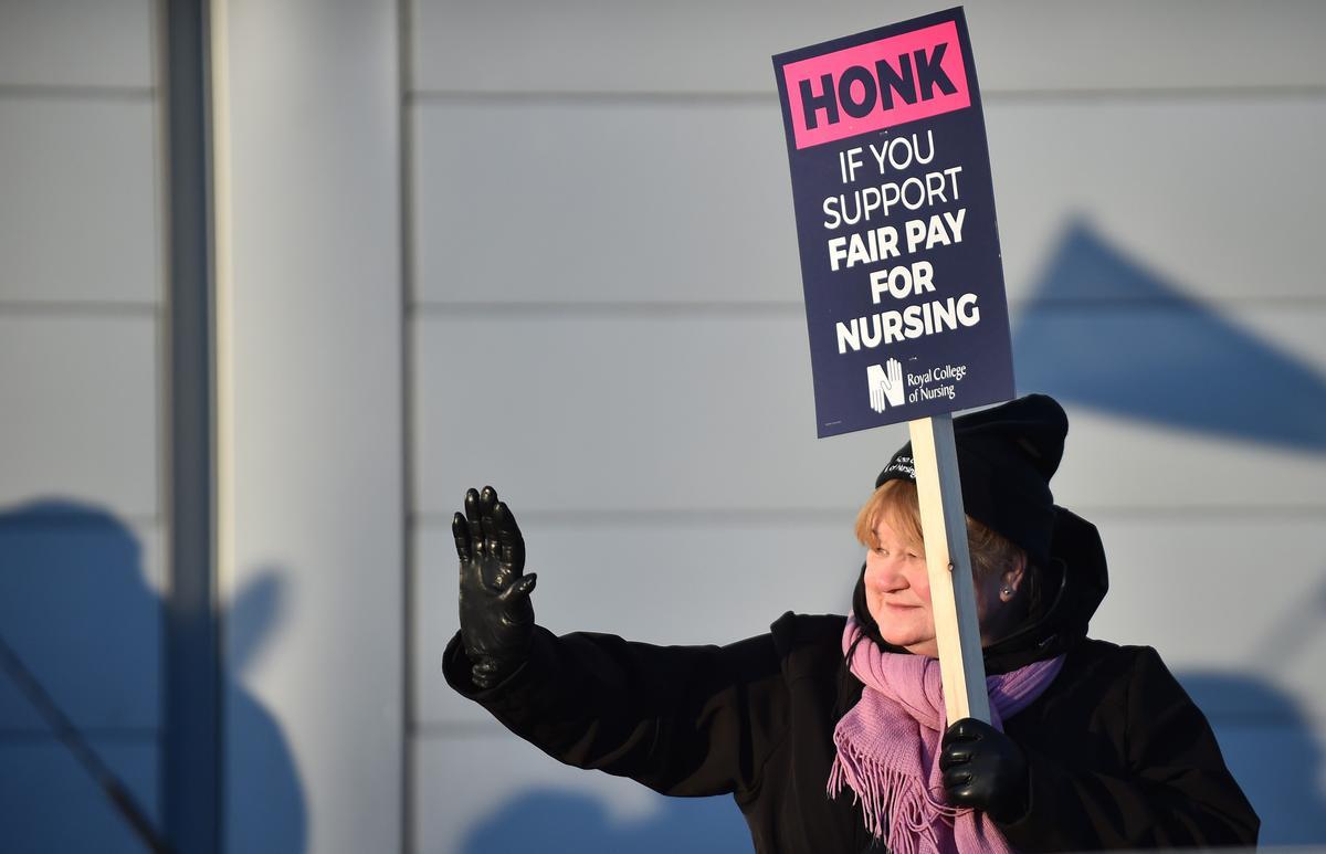 Una enfermera miembro del Royal College of Nursing (RCN) sostiene una pancarta durante la manifestación del colectivo a las puertas del Royal Liverpool University Hospital, en Liverpool.