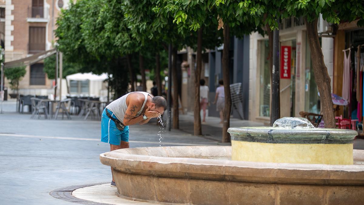 Un hombre se echa agua en la cara de una fuente del centro de Murcia para refrescarse, este lunes por la mañana.