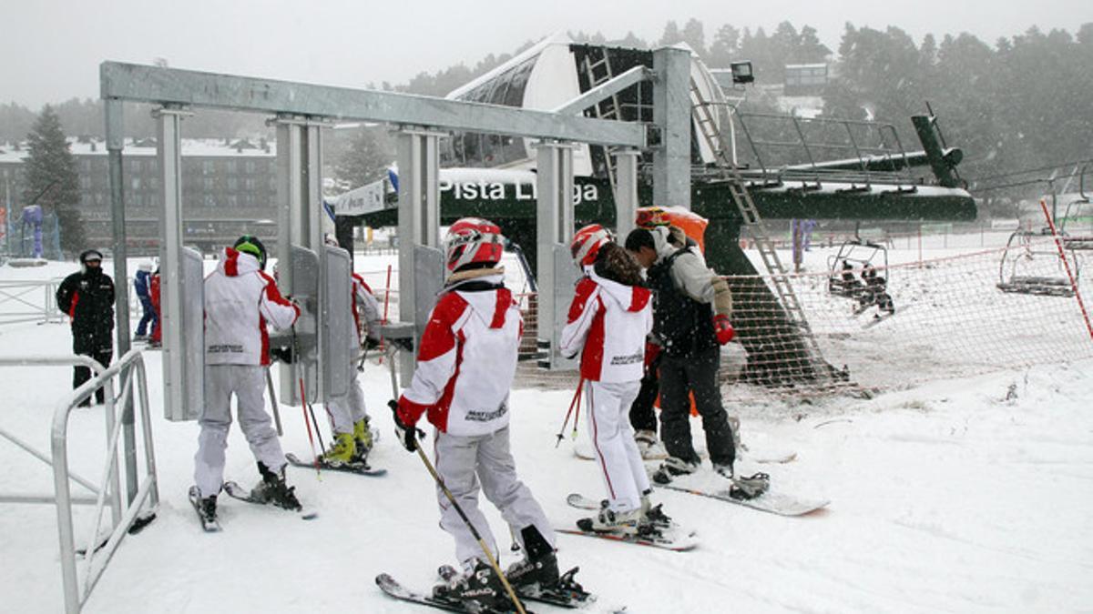 Un grupo de esquiadores pasa por el torno para acceder a un telesilla, en La Molina