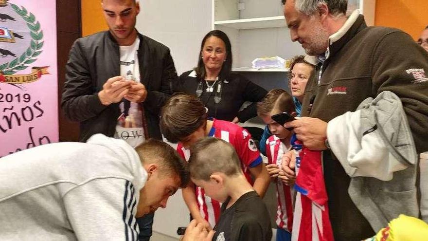 Dani Martín, de pie a la izquierda, y Nacho Méndez, agachado, firmando un autógrafo en la camiseta del pequeño Gonzalo, ayer en Pravia.