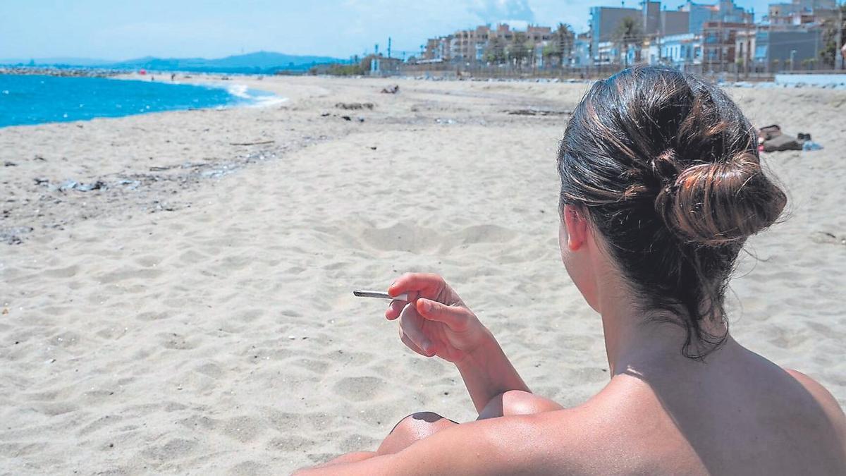 Una jove sosté una cigarreta en una platja de Premià de Mar