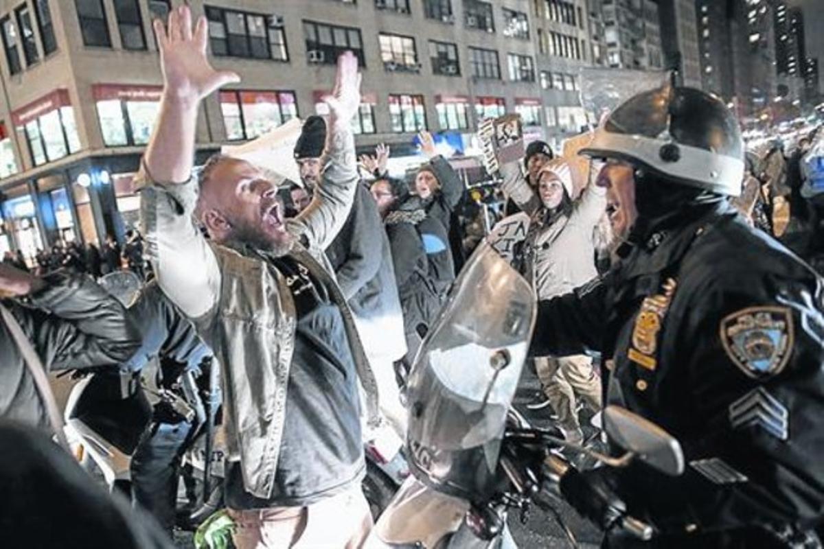 Un manifestant s’encara a un policia antiavalots a la Sisena Avinguda de Nova York durant la protesta per la sentència judicial, ahir.