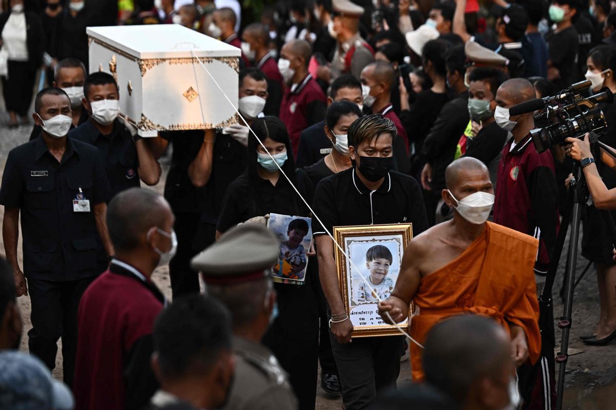 La gente observa cómo las piras funerarias incineran a 19 víctimas del tiroteo en la guardería de Uthai Suwan en el templo Wat Rat Samakee en Uthai Sawan. Un exoficial de policía disparó y mató a 37 personas, al menos 24 de ellos niños, después de irrumpir en una guardería infantil en el noreste de Tailandia.