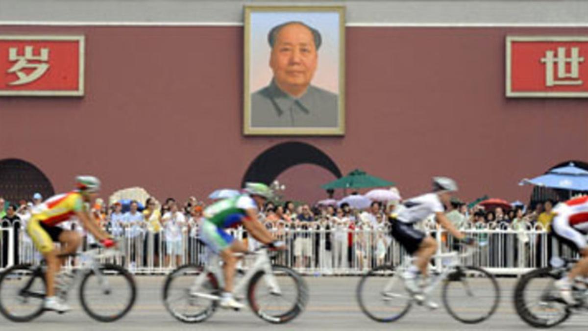 Varios ciclistas pasan delante del retrato de Mao en la plaza de Tiananmen, esta mañana en Pekín.