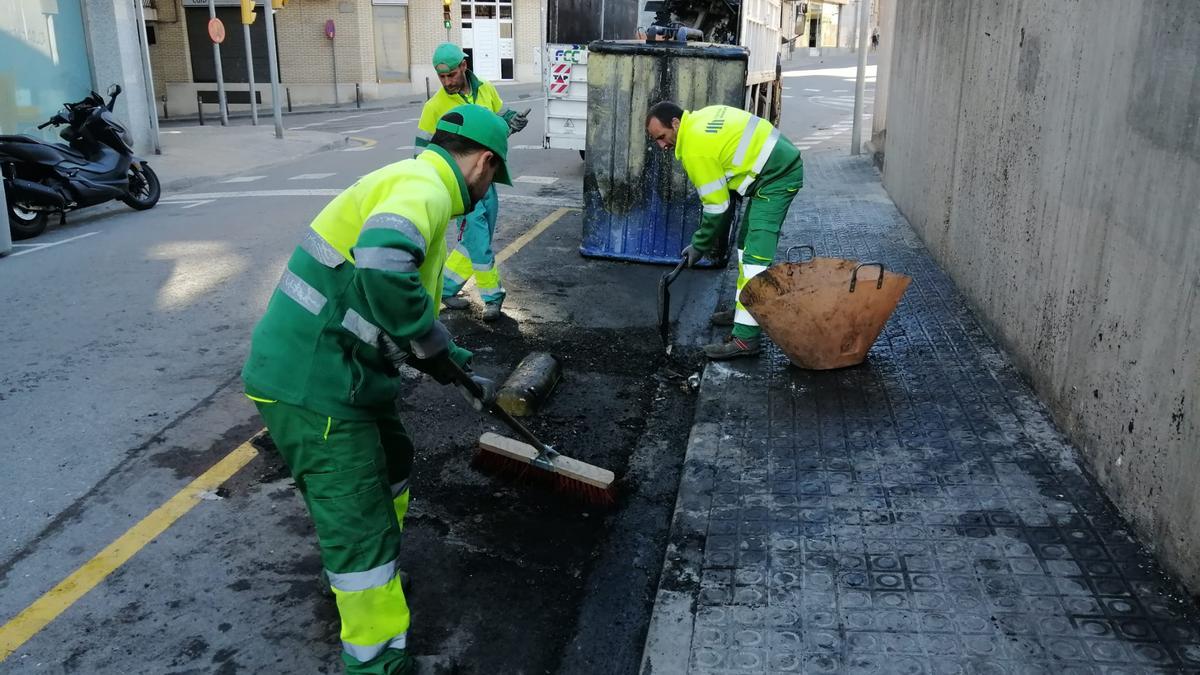 El servei de neteja municipal treballa per retirar les restes dels contenidors calcinats