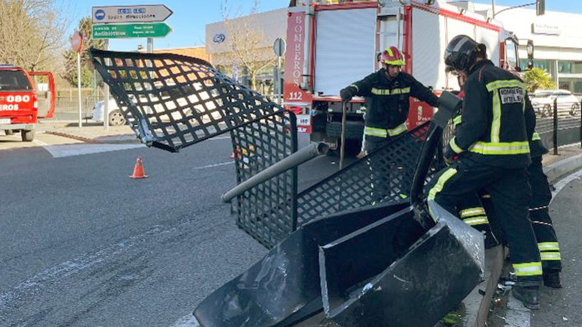 Los bomberos retiran el mobiliario urbano dañado por un turismo que impactó contra la valla de protección de la rotonda de Michaisa en León