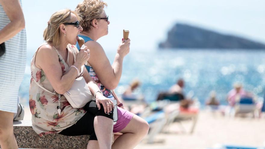 Dos mujeres mitigan el calor comiendo un helado en la playa de Levante de Benidorm