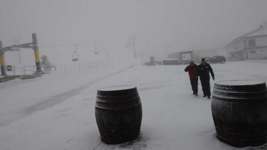 Dos trabajadores pasean por el complejo invernal de Valgrande-Pajares tras la primera gran nevada que cayó sobre sus pistas.