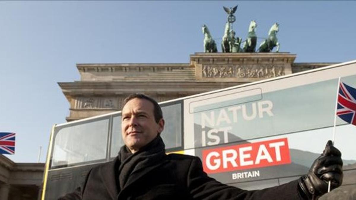 El embajador británico en Berlin, Simon McDonald, aguanta dos banderas delante de las Puertas de Bradenburgo.