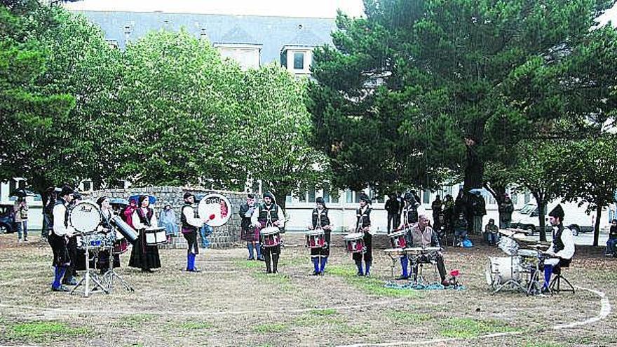 La sección de percusión de las bandas de gaitas Llariegu y Noega durante su actuación bajo una fuerte tormenta.