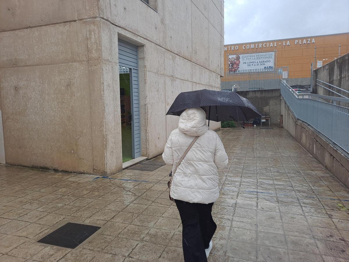 Una mujer se protege del granizo con su paraguas, en la puerta del colegio Nuestra Señora de Bótoa.