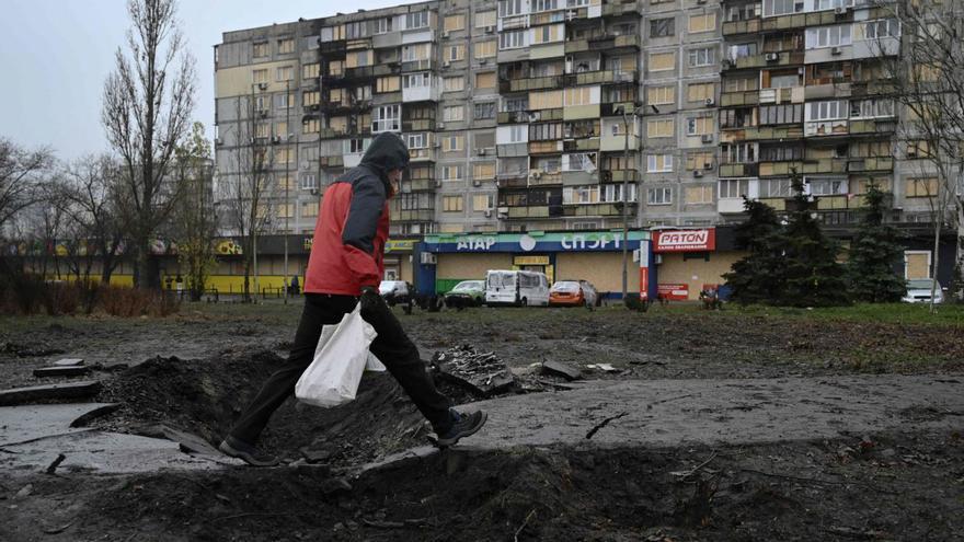 Un home passa sobre un cràter causat per una bomba d’un atac aeri, ahir a Kíiv.  |  GENYA SAVILOV / AFP