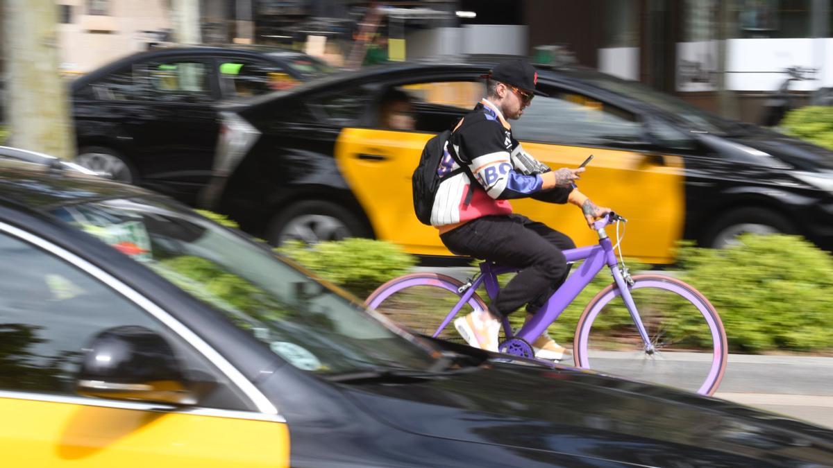 Un ciclista consulta su teléfono mientras circula por el carril bici de la Diagonal, este miércoles