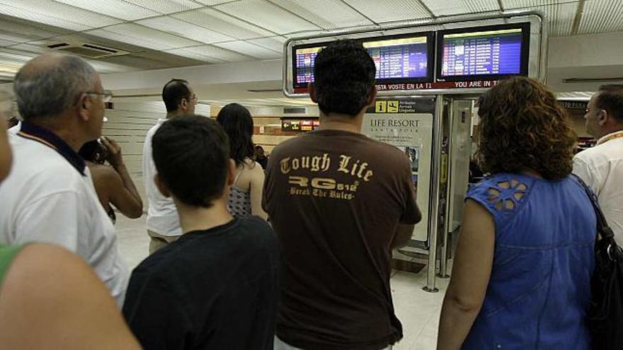 Pasajeros de El Altet observan los paneles informativos para conocer el estado de sus vuelos, ayer por la mañana.