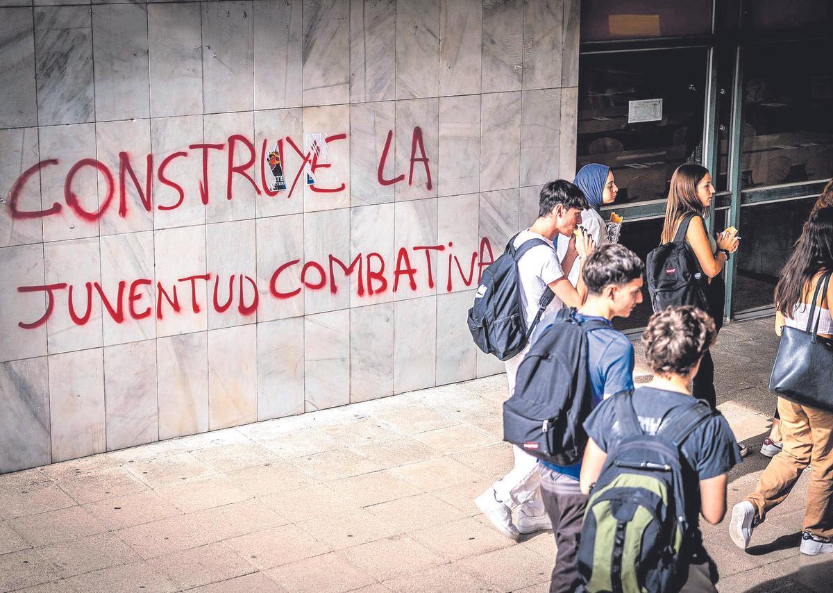 Un grupo de jóvenes delante de una pintada política en Barcelona