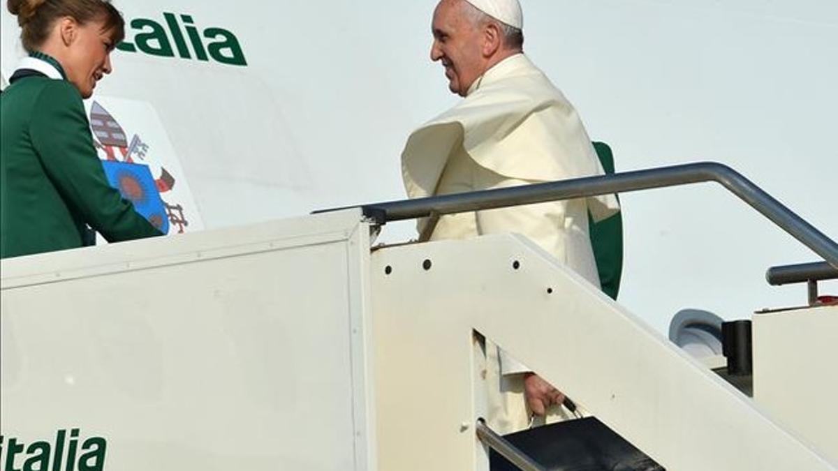 Una azafata da la bienvenida al Papa al subir a bordo del avión que le traslada a Brasil.