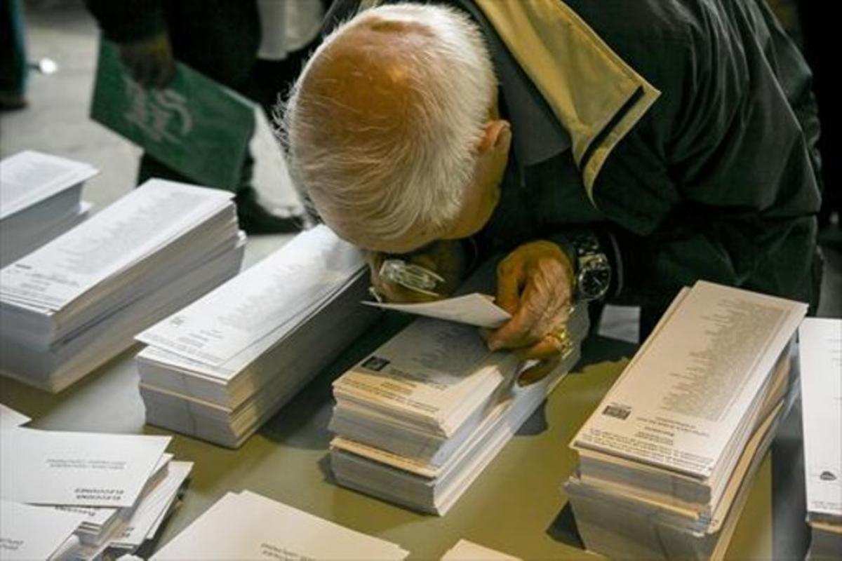 Un ciudadano examina con una lupa una papeleta electoral en Barcelona.