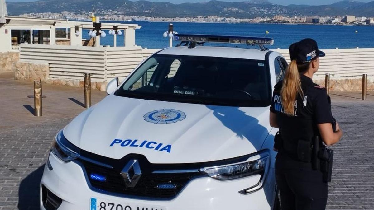 Una agente de la Policía Local de Palma, junto a su coche patrulla.