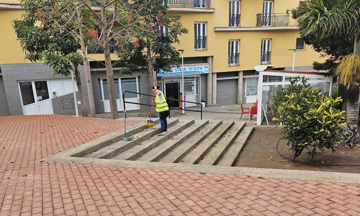 Una trabajadora de un programa municipal, barriendo una plaza en Las Huertas de Guía.