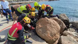 Retiran con una grúa una de las piedras del paseo marítimo para liberar a un hombre en Torrevieja