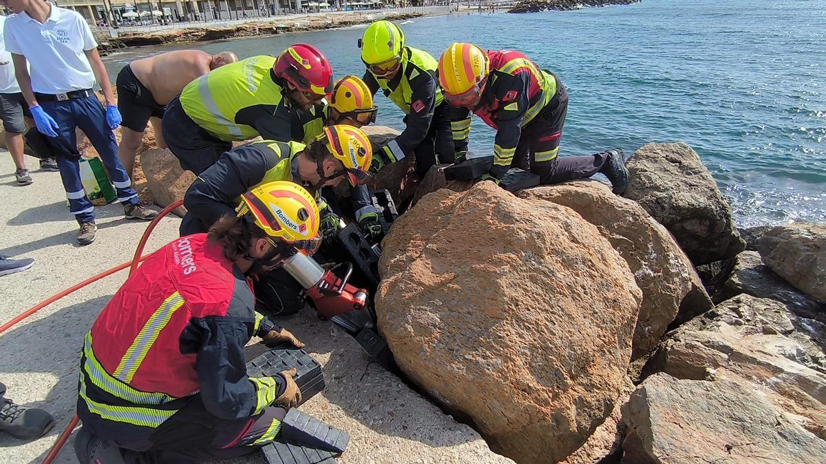 Así han liberado los bomberos a un bañista que se ha colado entre las rocas del paseo de Torrevieja en un complicado rescate