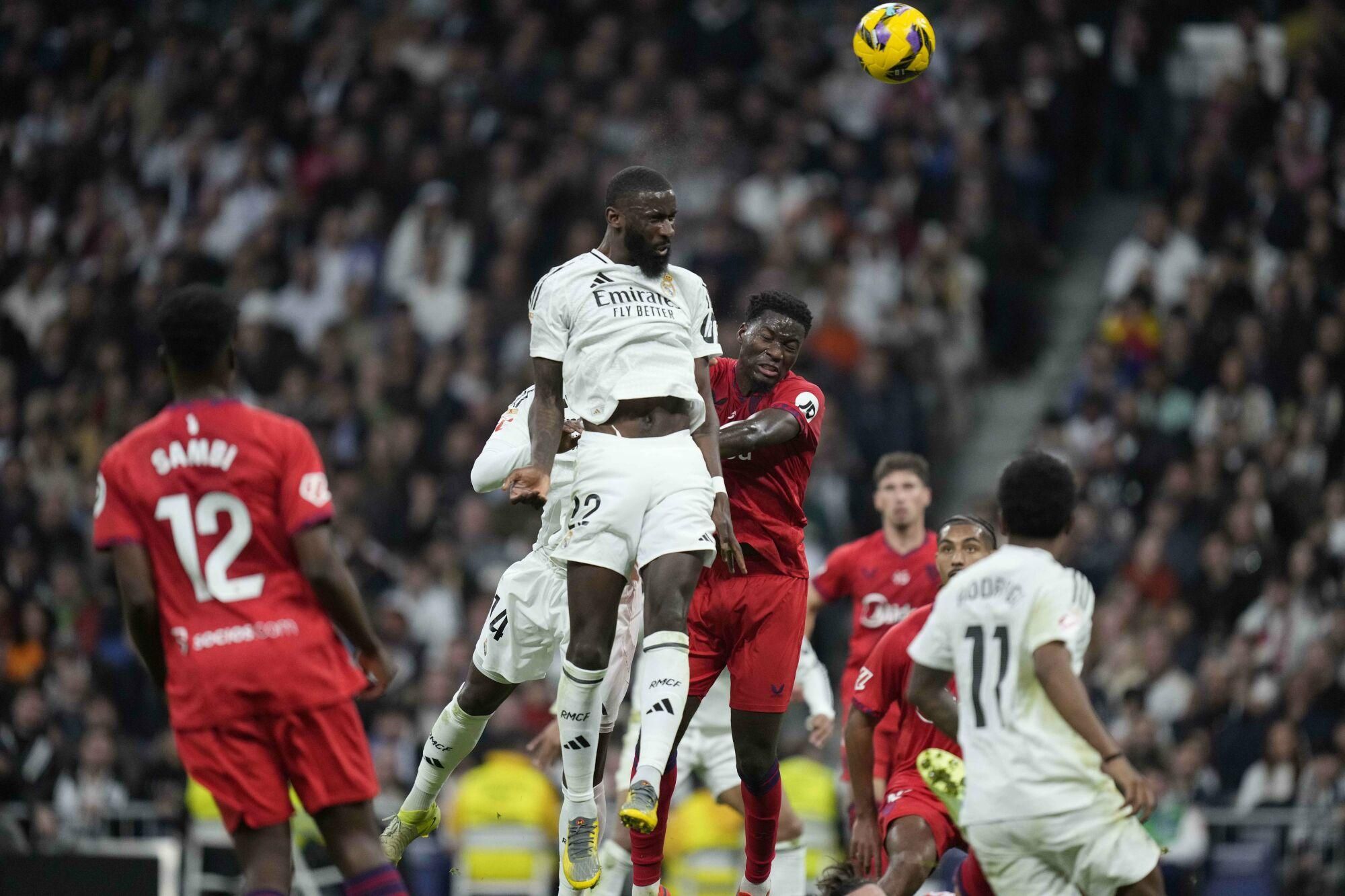 Real Madrid's Antonio Rudiger goes for the header with Sevilla's Lucien Agoume during the Spanish La Liga soccer match between Real Madrid and Sevilla at the Santiago Bernabeu Stadium in Madrid, Spain, Sunday, Dec. 22, 2024. (AP Photo/Bernat Armangue). EDITORIAL USE ONLY / ONLY ITALY AND SPAIN