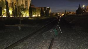 Carrito de compra de un supermercado y tapa de hierro del servicio de agua potable sobre las vías del tren en Elche
