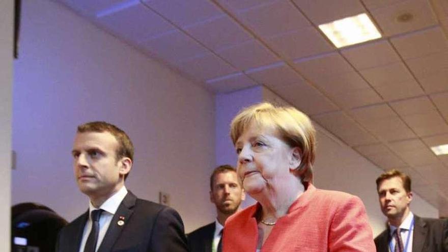 Macron y Merkel, camino de la rueda de prensa conjunta que ofrecieron ayer al finalizar la cumbre de la UE en Bruselas.