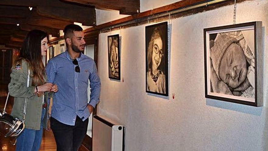 Dos jóvenes de Toledo observan algunos de los cuadros de la exposición de Mer Fidalgo