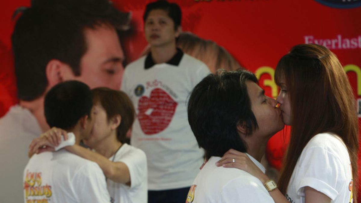 Dos parejas tailandesas, observadas por un juez, participan en el concurso para batir el récord del beso más largo, en Pattaya.