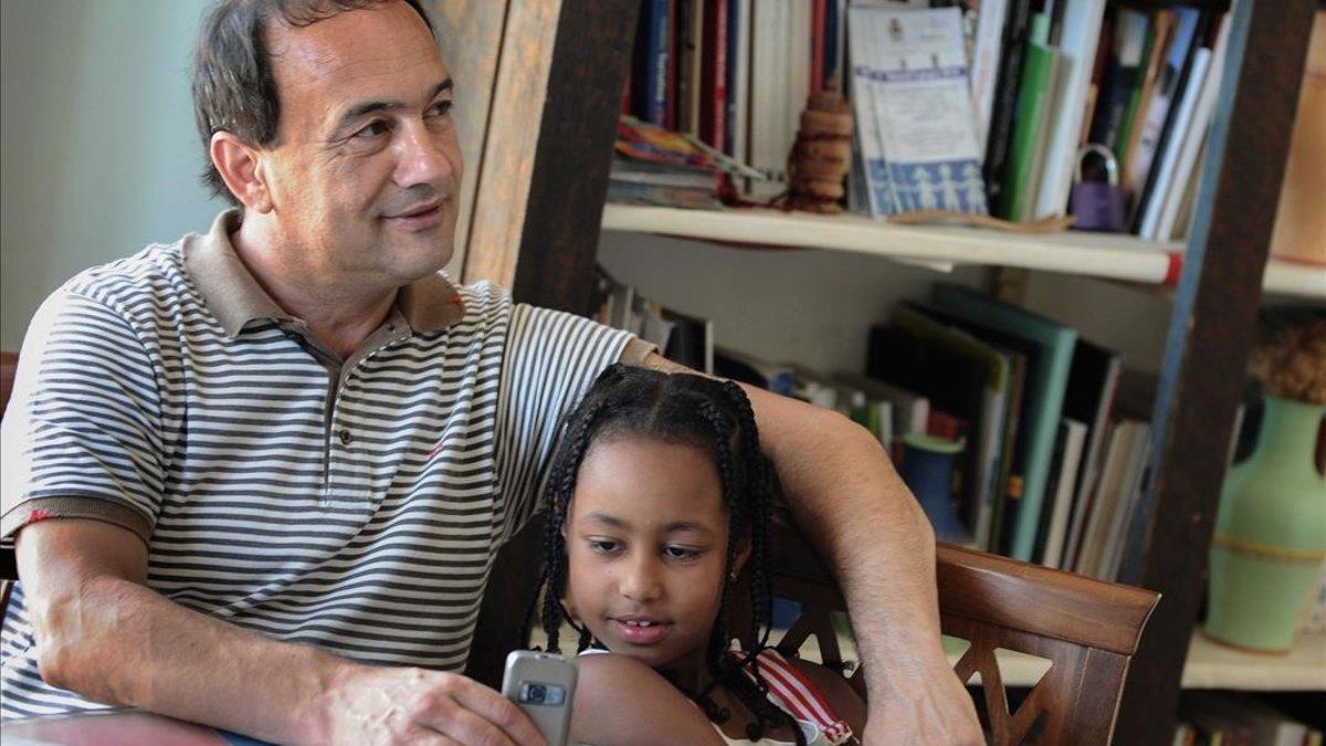 Domenico Lucano, exalcalde de Riace, posa con una niña etíope.