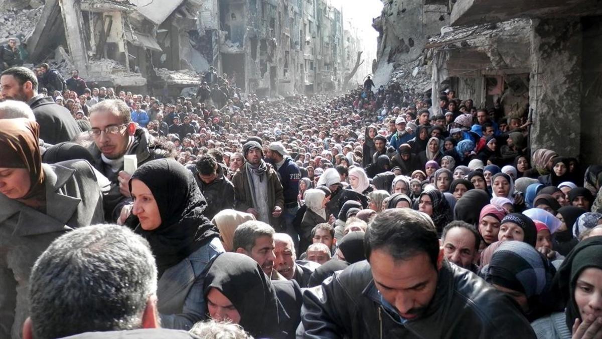 Palestinos refugiados del campo de Yarmouk, en Siria, hacen cola en enero del 2014 para recibir alimentos.