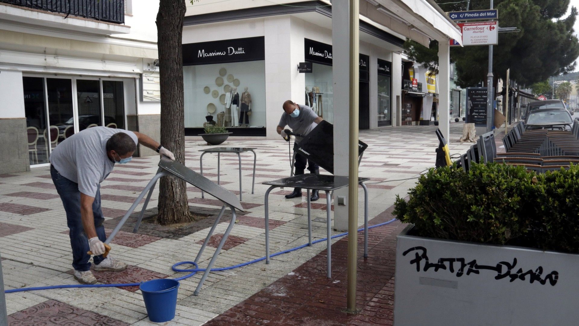 Trabajadores de un bar de Platja d'Aro limpian sillas y mesas de una terraza, en mayo del año pasado.