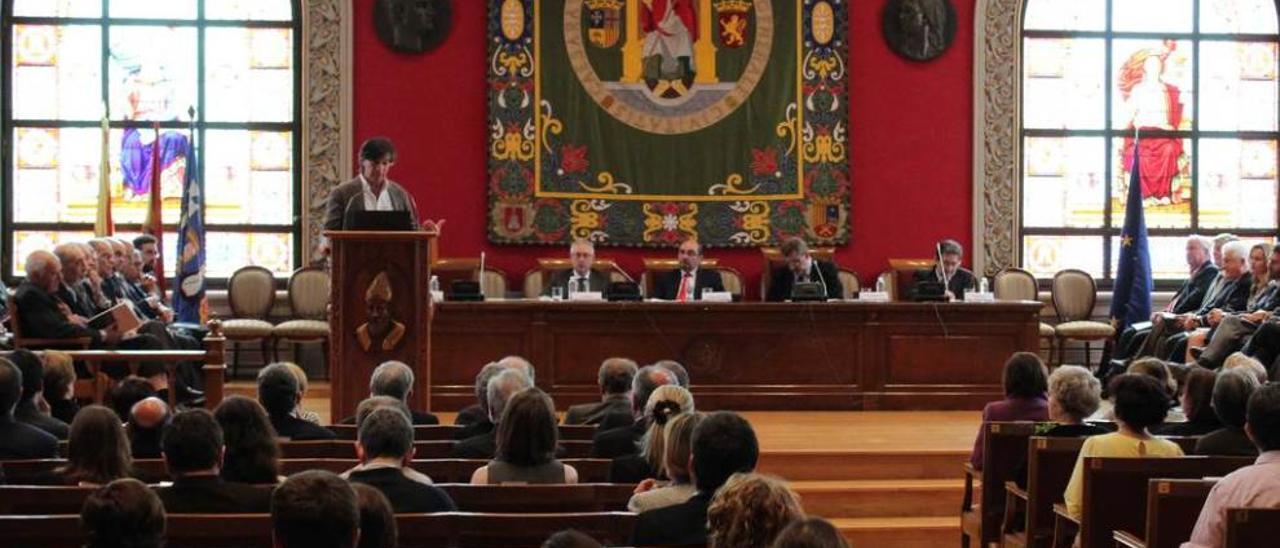 López Otín, al fondo, durante su conferencia en el paraninfo universitario.