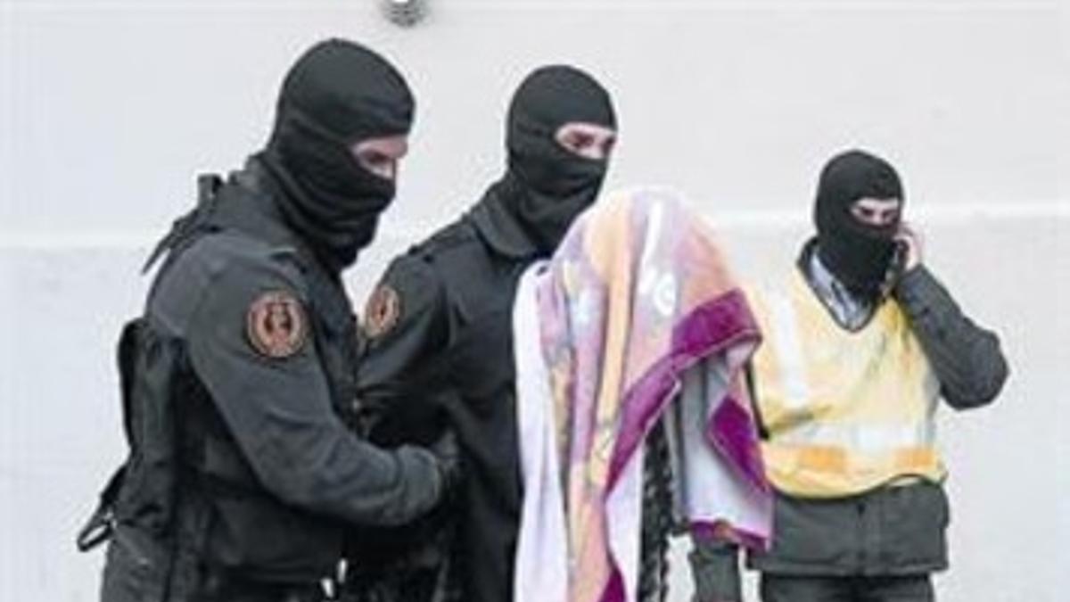 Agentes de la Guardia Civil trasladan a la madre detenida del domicilio de Badalona al vehículo que la llevó a Madrid.