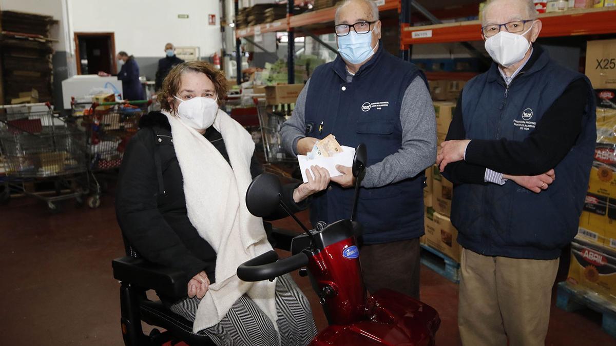 Ana Estévez, en su nueva moto adaptada, entrega ayer en el Banco de Alimentos de Vigo el dinero recaudado